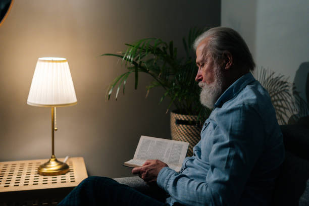 A cosy armchair with a warm reading lamp and an open book at night